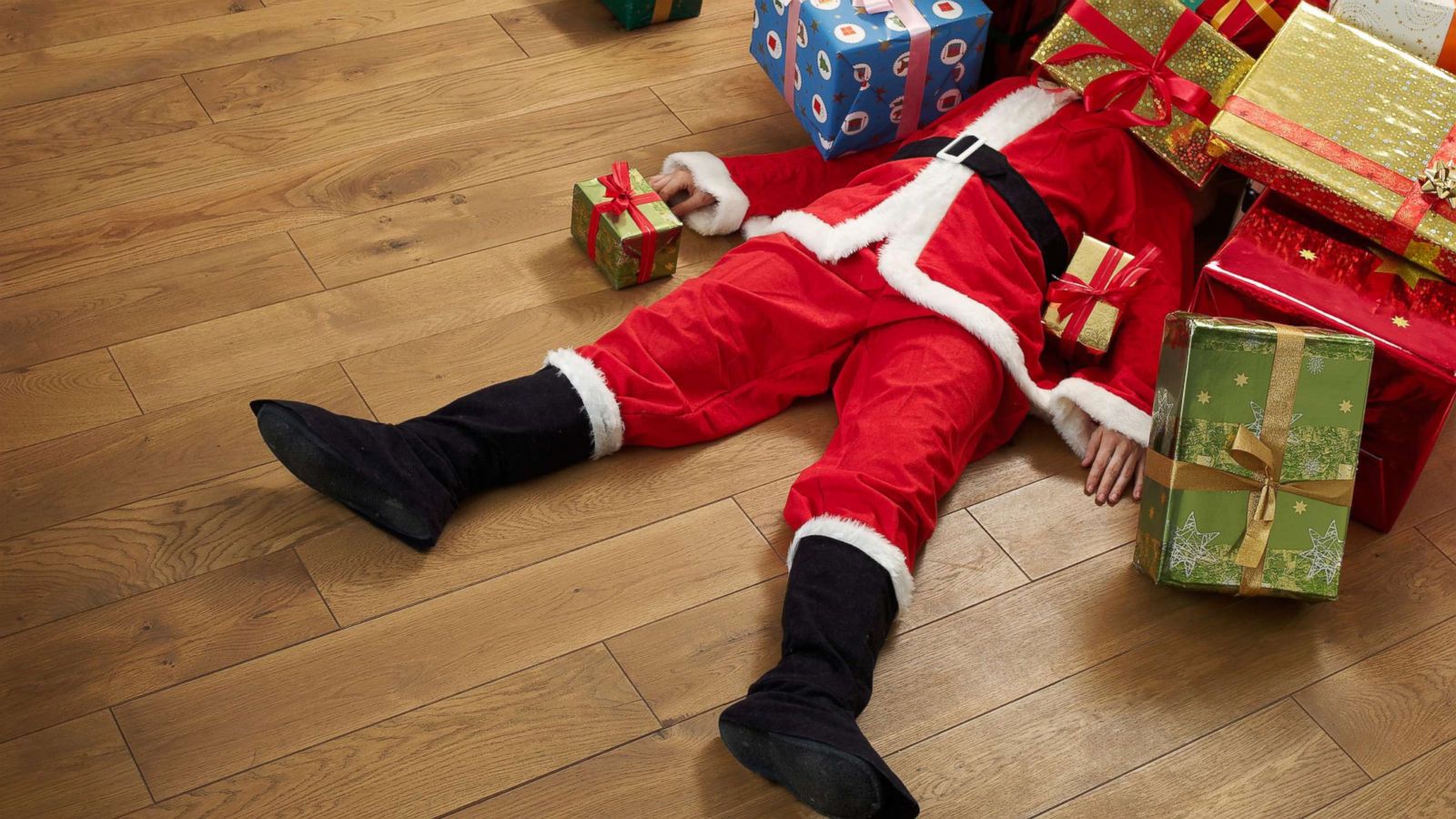 PHOTO: A stock photo depicts a person dressed as Santa Claus buried under a pile of Christmas presents.