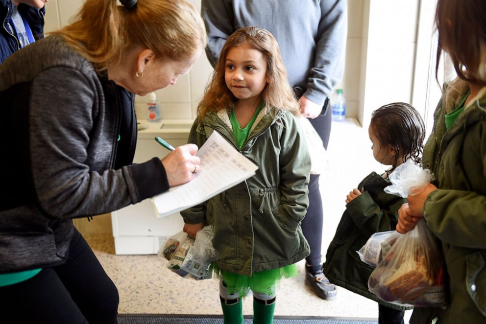 PHOTO: A member of the food service staff records the names of children who are picking up lunches and educational packets at the West Reading Elementary Center in West Reading, Pa., March 17, 2020.