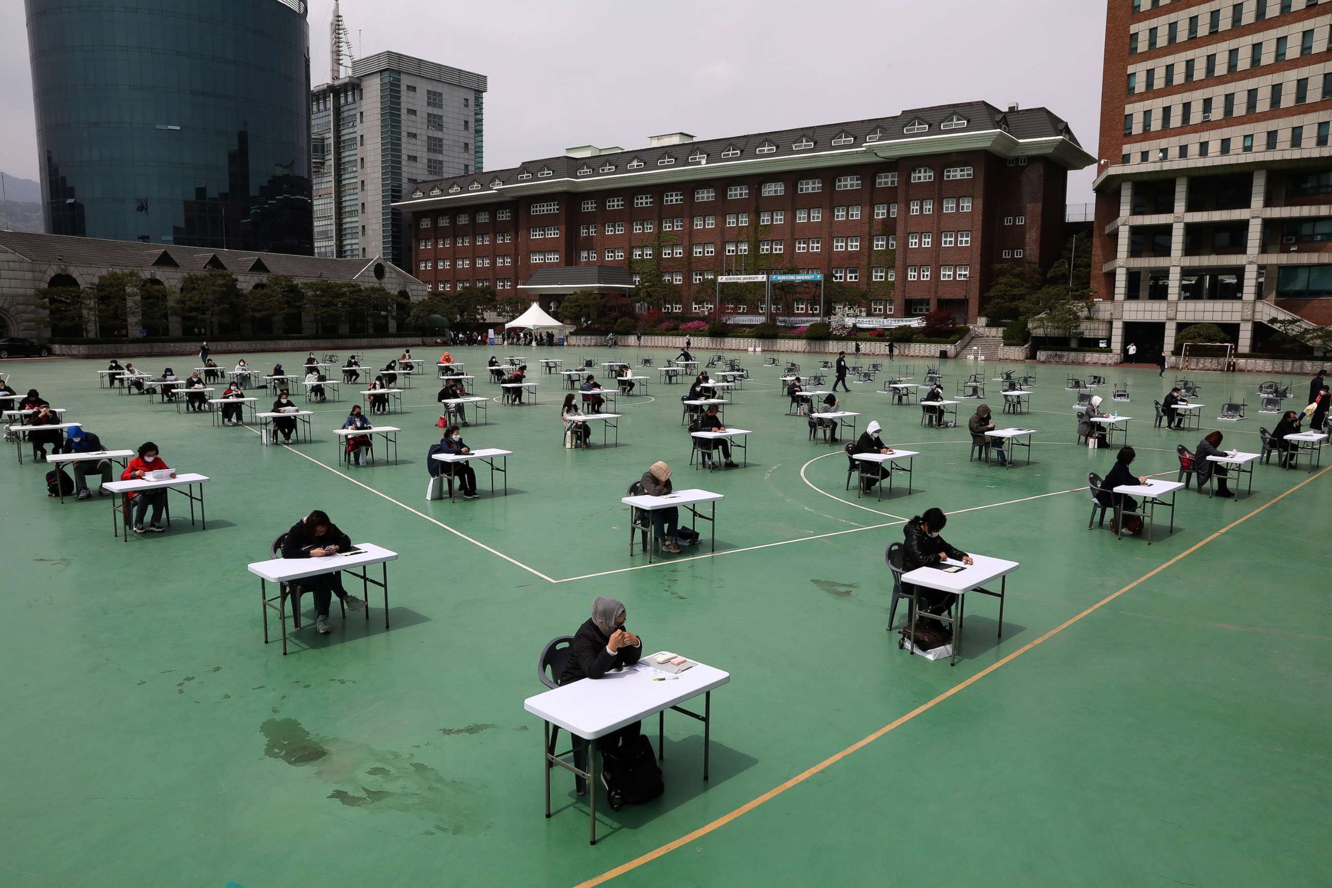 PHOTO: South Koreans wear masks and sit according to social distancing as a preventive measure against the coronavirus at Seokyeong University playground on April 25, 2020 in Seoul.