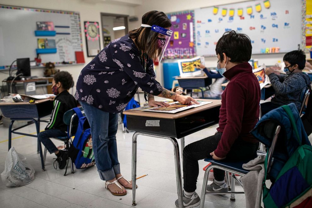 PHOTO: Teacher Elizabeth DeSantis, wearing a mask and face shield, helps a first grader during reading class at Stark Elementary School on Sept. 16, 2020 in Stamford, Conn.