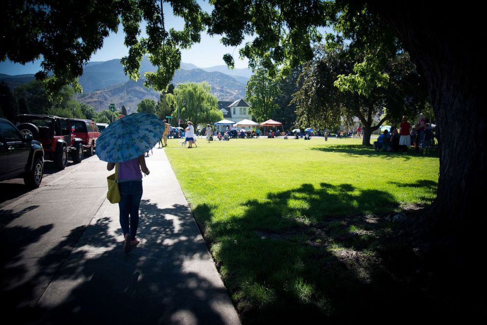 PHOTO: A girl carrying a parasol walks along a street.