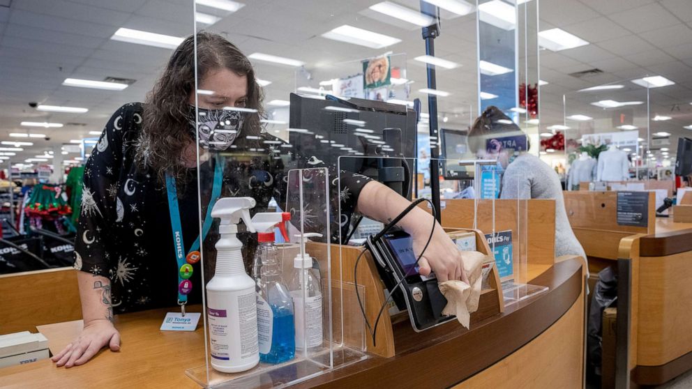 PHOTO: An employee wearing a protective mask disinfects the credit card reader at a checkout counter at a Kohl's department store in Woodstock, Ga., Nov. 23, 2020. 