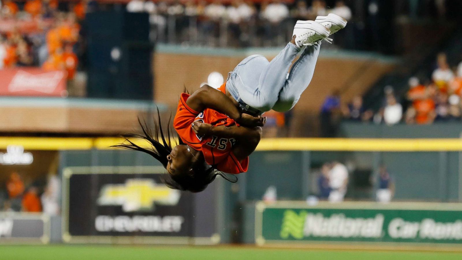 PHOTO: Olympian Simone Biles does a flip as she throws out the ceremonial first pitch before the start of the Houston Astros and Washington Nationals MLB 2019 World Series game two at Minute Maid Park in Houston, Texas, Oct. 23, 2019.