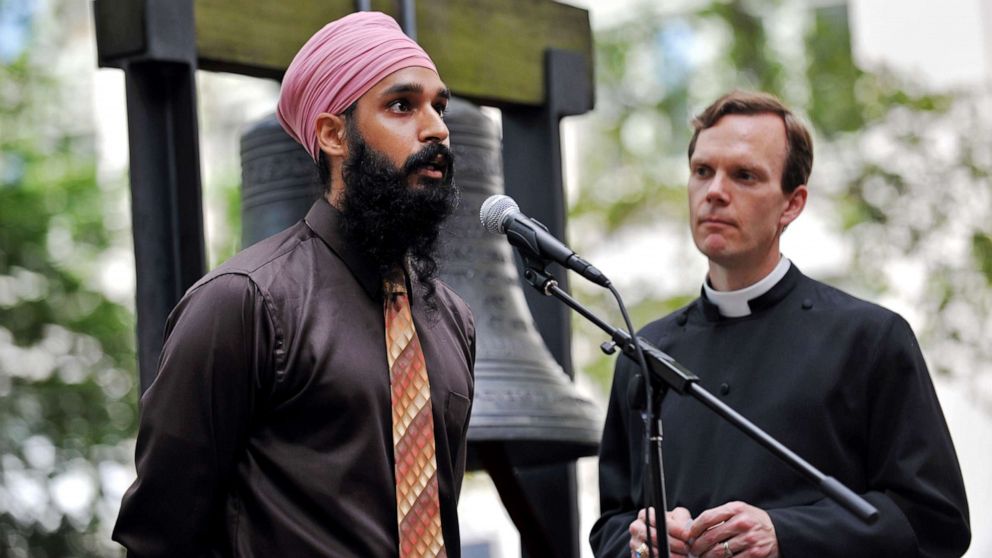 PHOTO: Simran Jeet Singh (left) of the Sikh Coalition speaks as the Reverend Matthew Heyd of Trinity Wall Street listens in the courtyard of St. Paul's Chapel in New York on Aug. 10, 2012.