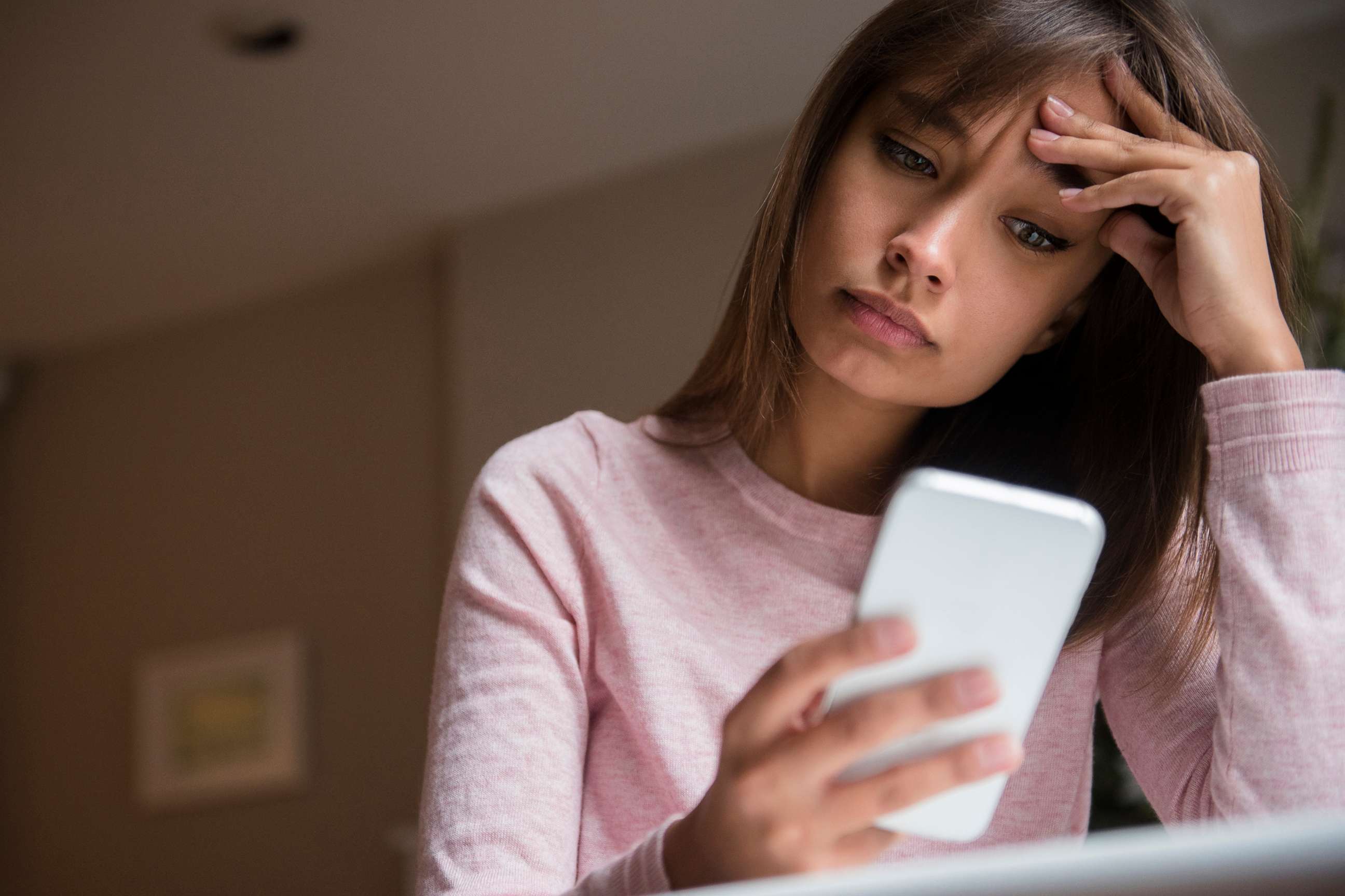 PHOTO: A stock photo of a concerned woman looking at a smartphone.