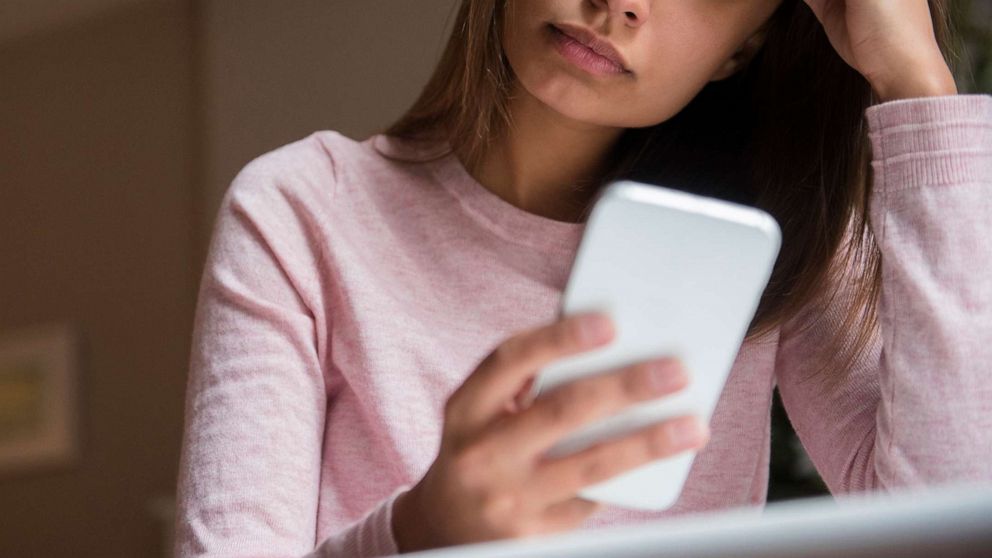 PHOTO: A stock photo of a concerned woman looking at a smartphone.