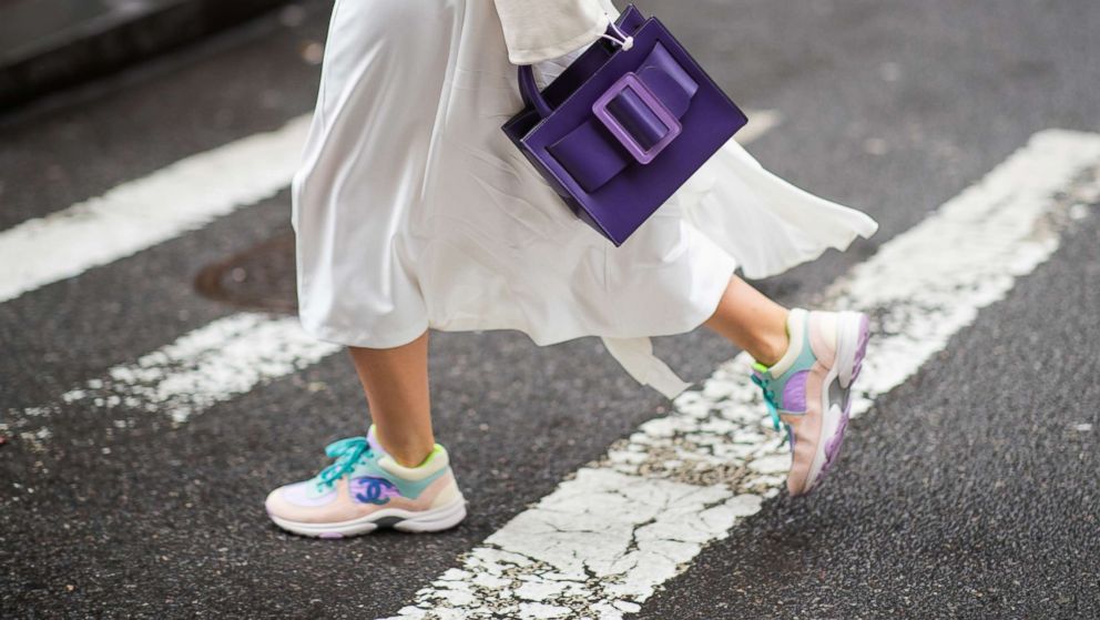 A guest is seen wearing purple Boyy bag, Chanel sneakers, and white skirt outside Kate Spade during New York Fashion Week Autumn Winter 2019, Feb. 8, 2019, in New York.