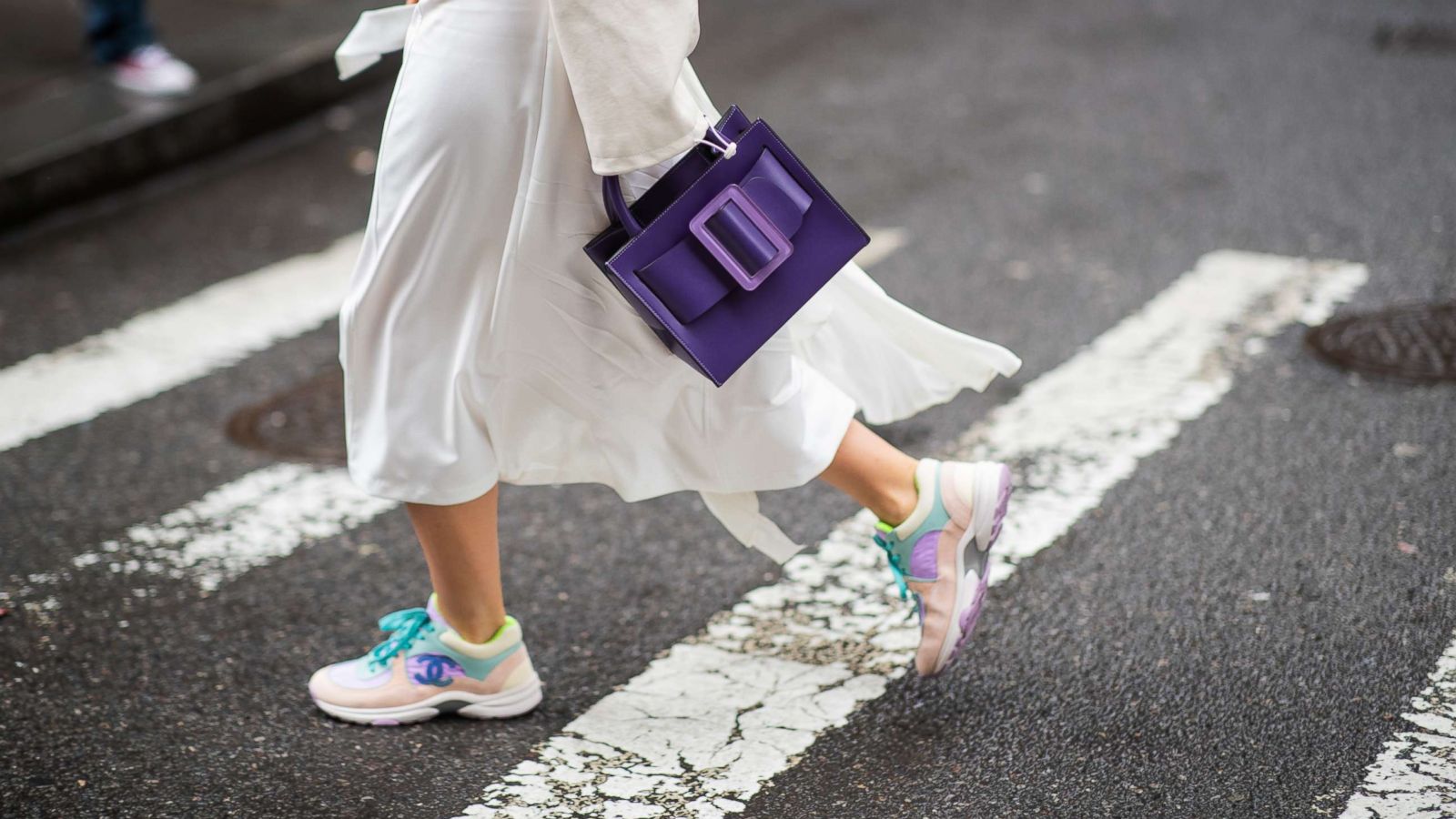 PHOTO: A guest is seen wearing purple Boyy bag, Chanel sneakers, and white skirt outside Kate Spade during New York Fashion Week Autumn Winter 2019, Feb. 8, 2019, in New York.