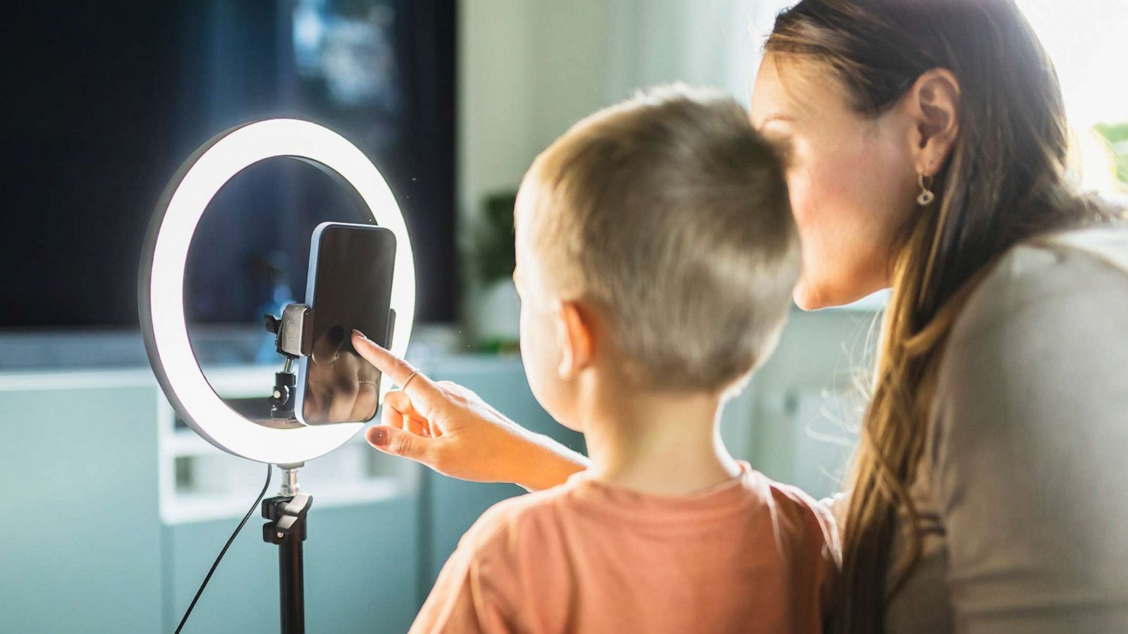 PHOTO: A stock photo shows a mother setting up a ring light and a mobile phone for live streaming with her son.