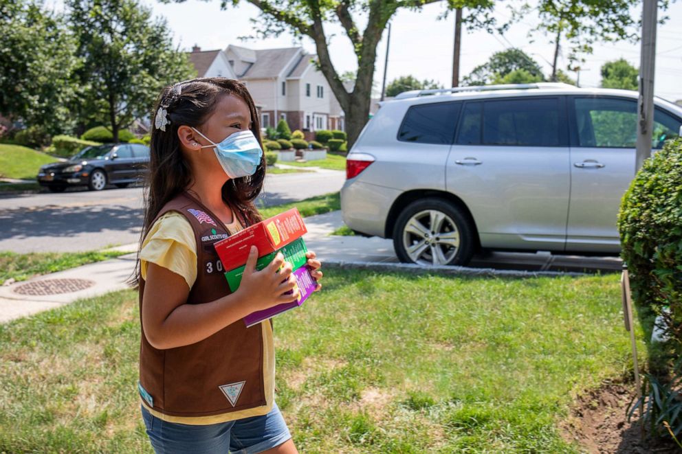 PHOTO: A Girl Scout carries boxes of cookies to be delivered to a customer from a safe distance. 