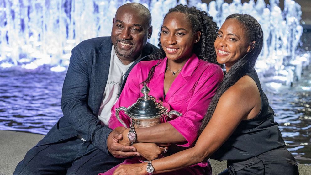 PHOTO: Coco Gauff winner of women's championship of US Open and parents pose with trophy in front of fountain at Billie Jean King Tennis Center.