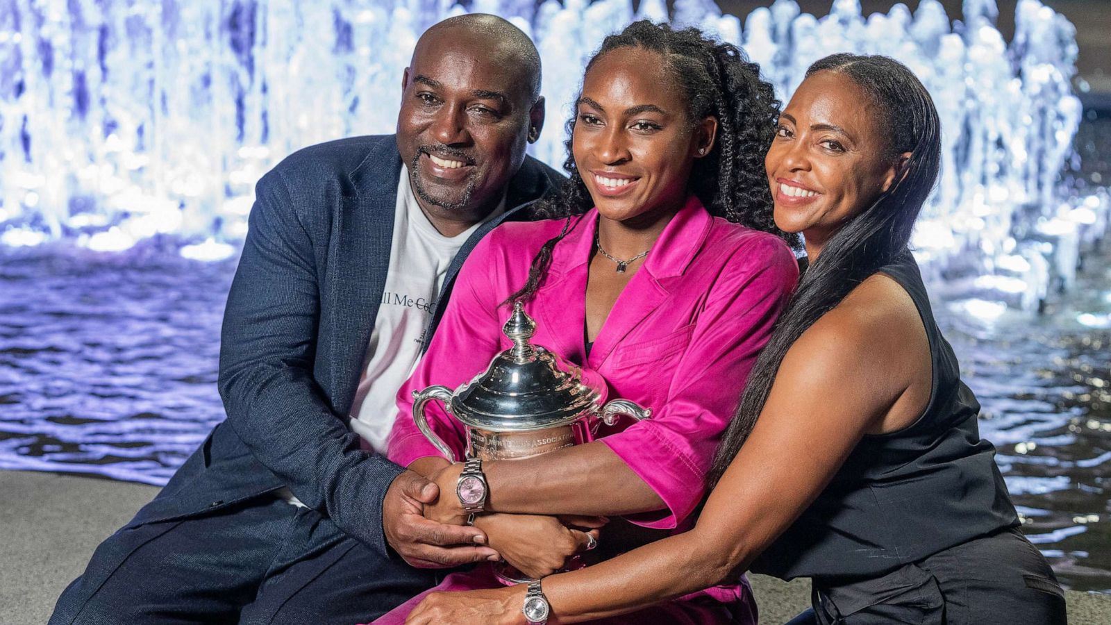 PHOTO: Coco Gauff winner of women's championship of US Open and parents pose with trophy in front of fountain at Billie Jean King Tennis Center.