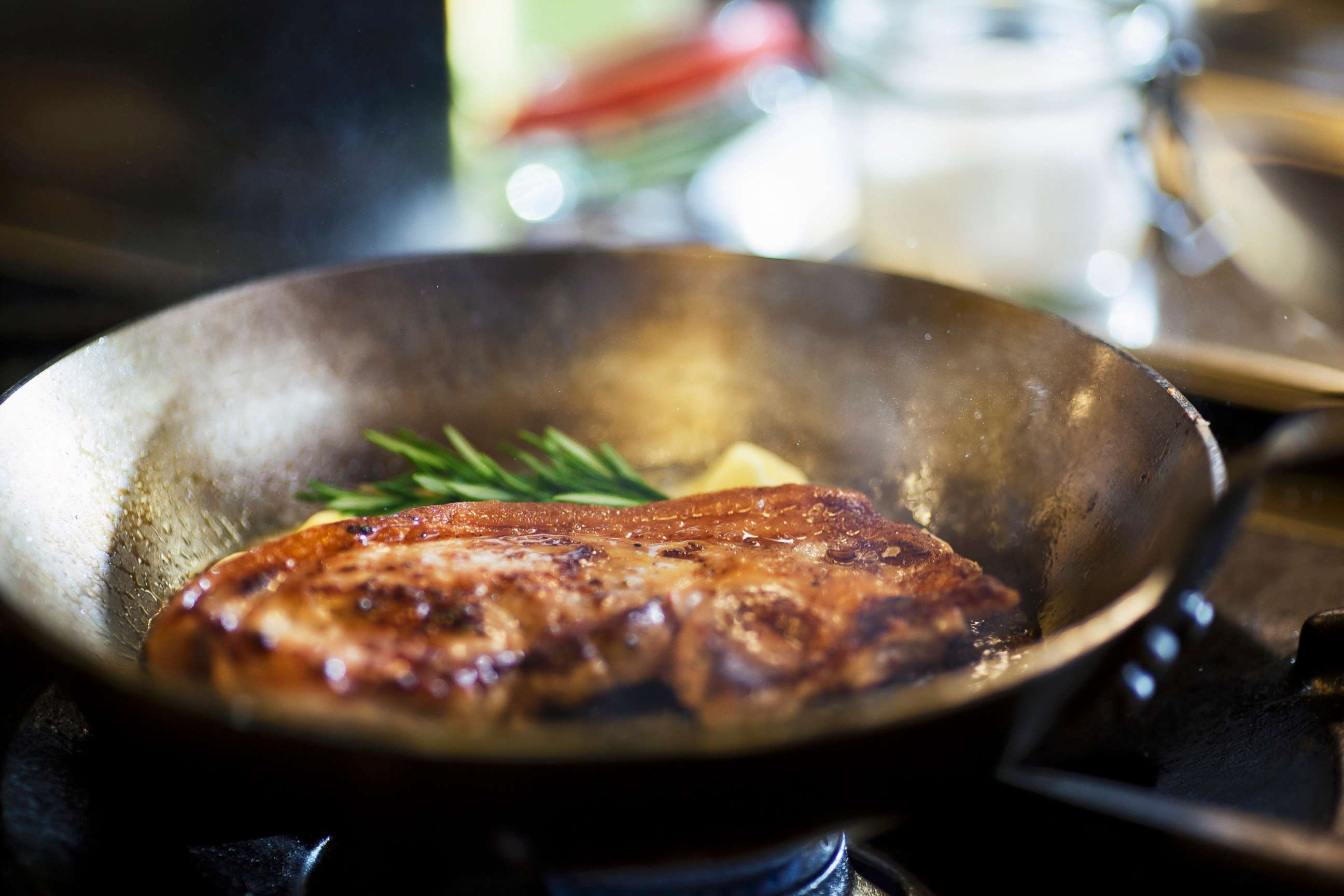 PHOTO: Steak cooking in a skillet with butter and herbs.