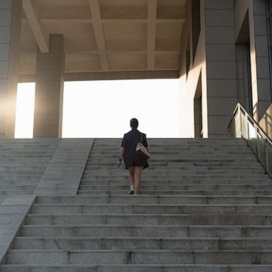 PHOTO: A woman walks up stairs in sunlight.