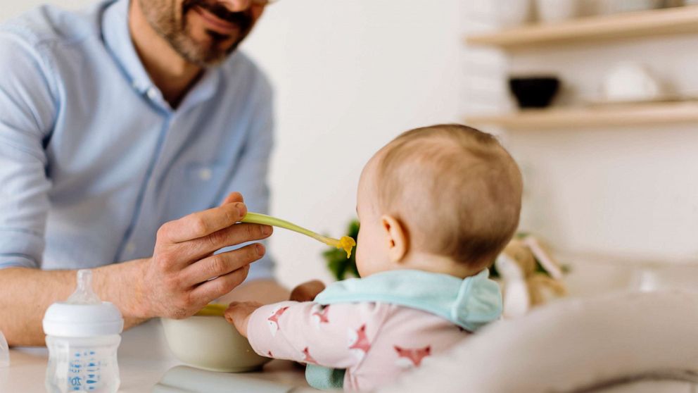 PHOTO: A father feeds a baby.