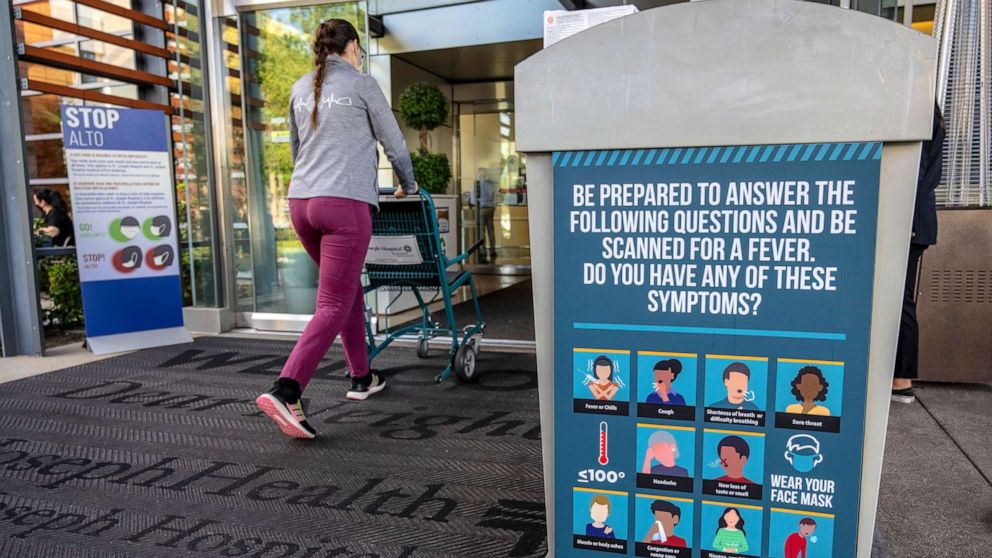 A woman walks past signs outside the emergency room entrance at Providence St. Joseph Hospital in Orange, Calif., Nov. 1, 2022. Orange County's health officer declared a local health emergency in response to increases in respiratory illnesses and RSV.