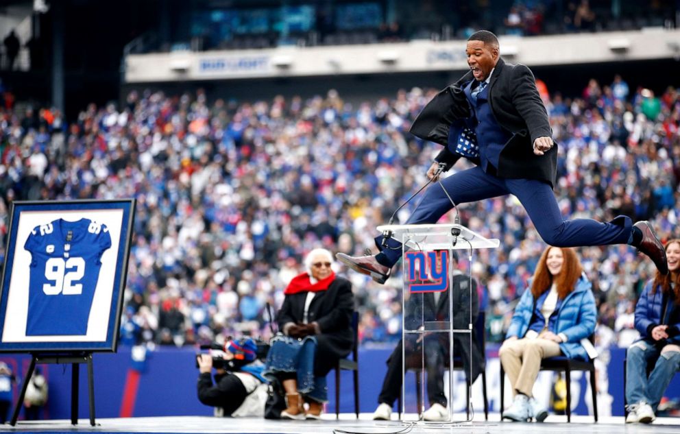 PHOTO: Former New York Giants player Michael Strahan jumps on the stage during the ceremony to retire his number at half time of the game between the Philadelphia Eagles and the New York Giants at MetLife Stadium, Nov. 28, 2021, in East Rutherford, N.J.