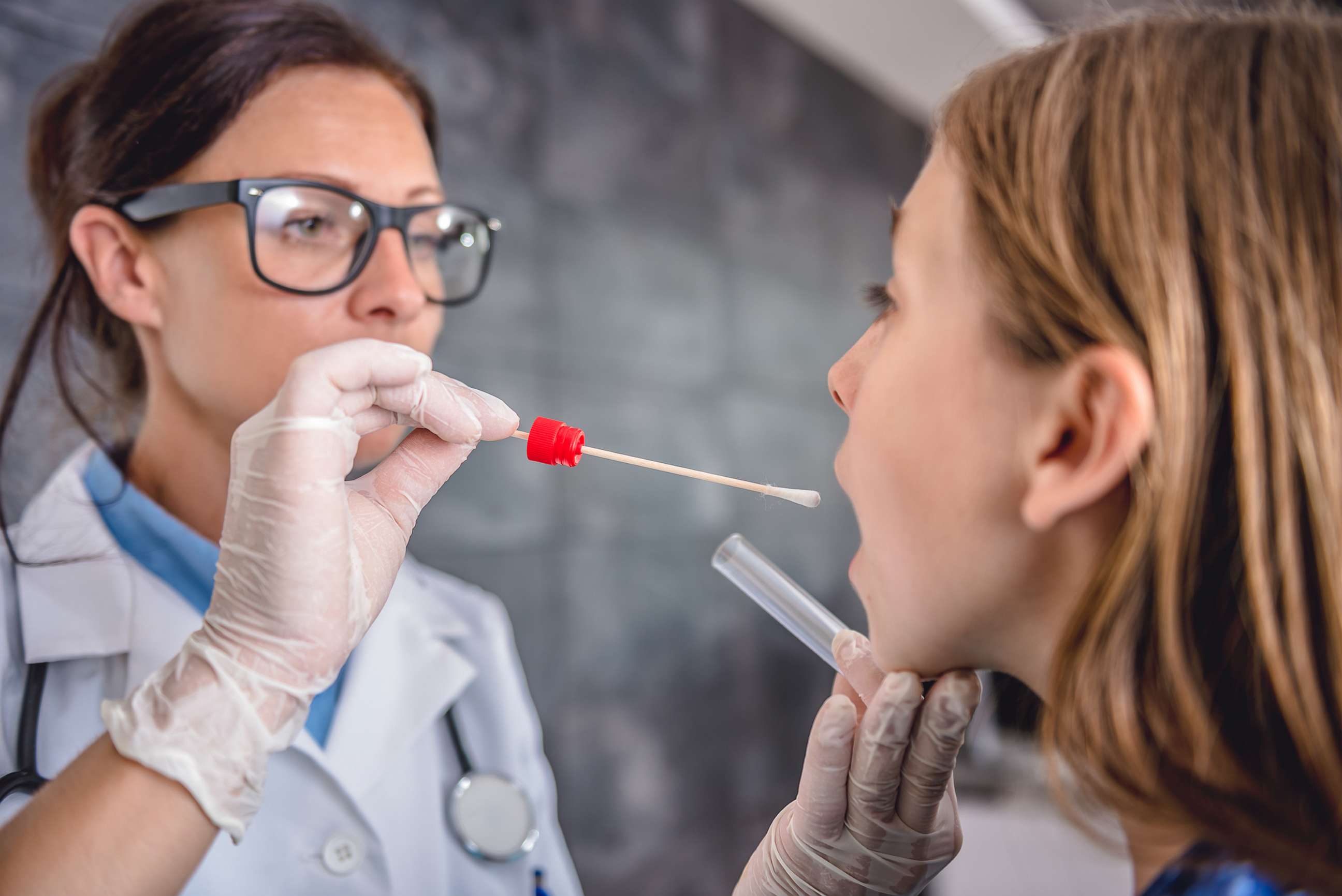 PHOTO: Female pediatrician using a swab to take a sample from a patient's throat