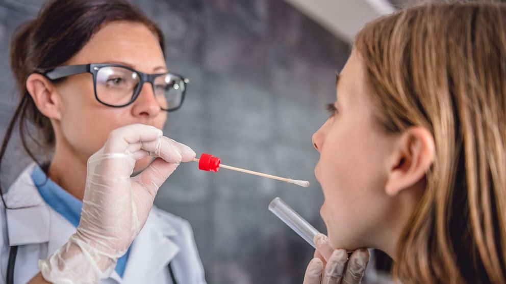 PHOTO: Female pediatrician using a swab to take a sample from a patient's throat