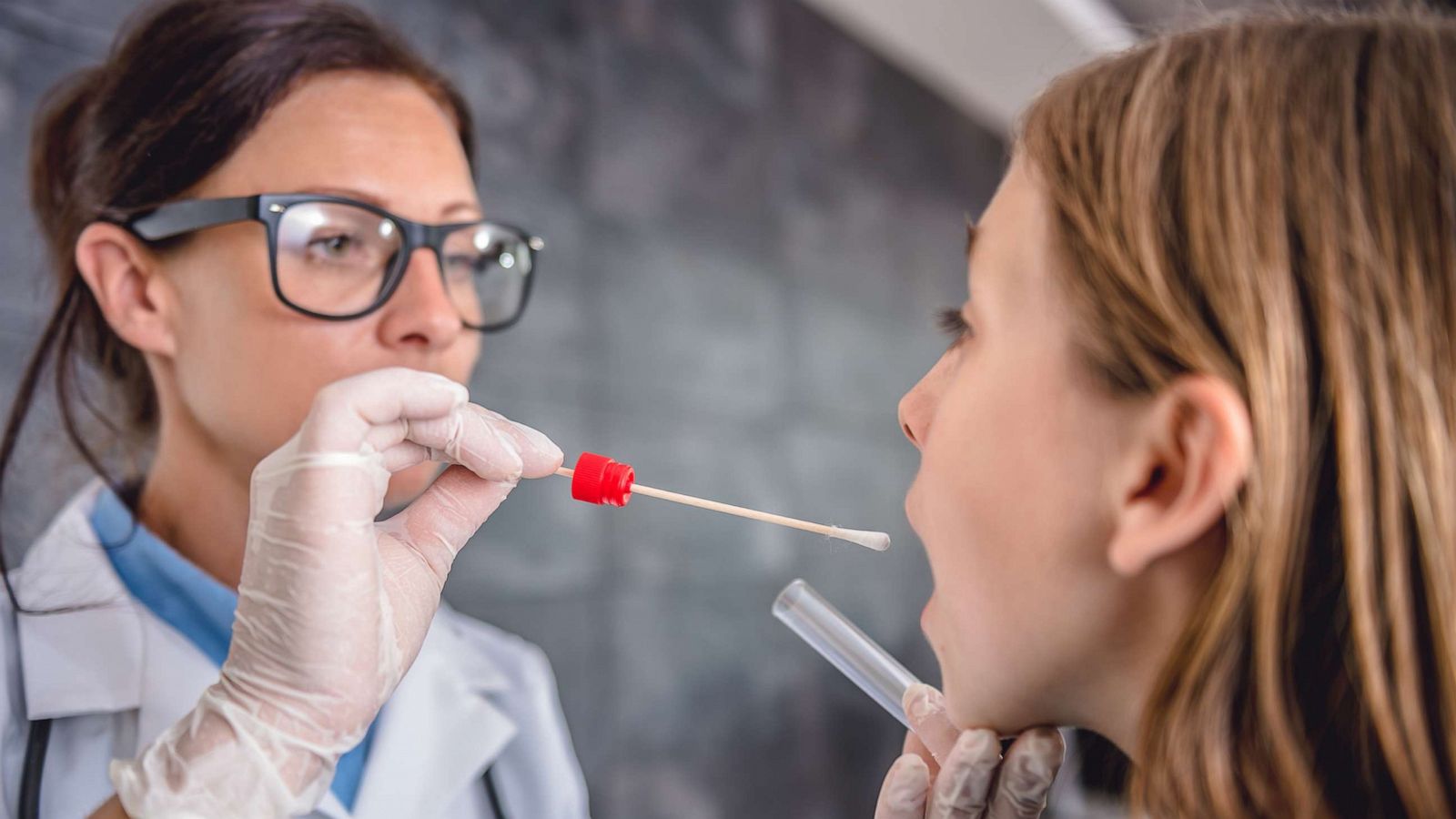 PHOTO: Female pediatrician using a swab to take a sample from a patient's throat