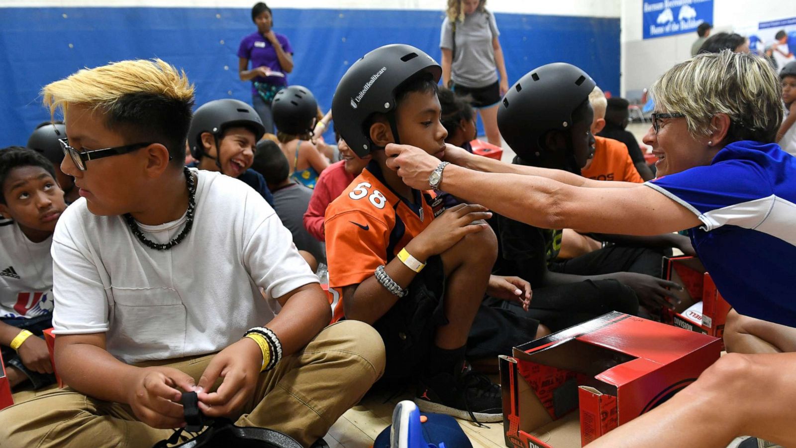 PHOTO: UHC Pro cyclist Lauren Hall helps a child with his helmet, which was donated by United Healthcare to all participants at the Denver Parks & Recreation Barnum Summer Day Camp in Denver, Aug.9, 2017.