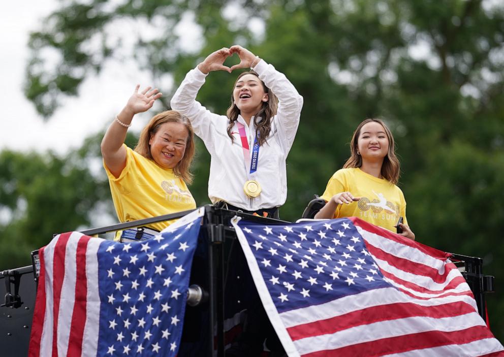 PHOTO: Sunisa Lee center with her mom Yeev Thoj and sister Shyenne Lee wave to the crowds along White Bear Avenue, August 8, 2021 in St. Paul, MN.