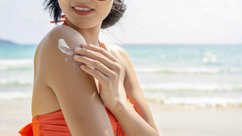 PHOTO: A woman applies sunscreen at the beach.