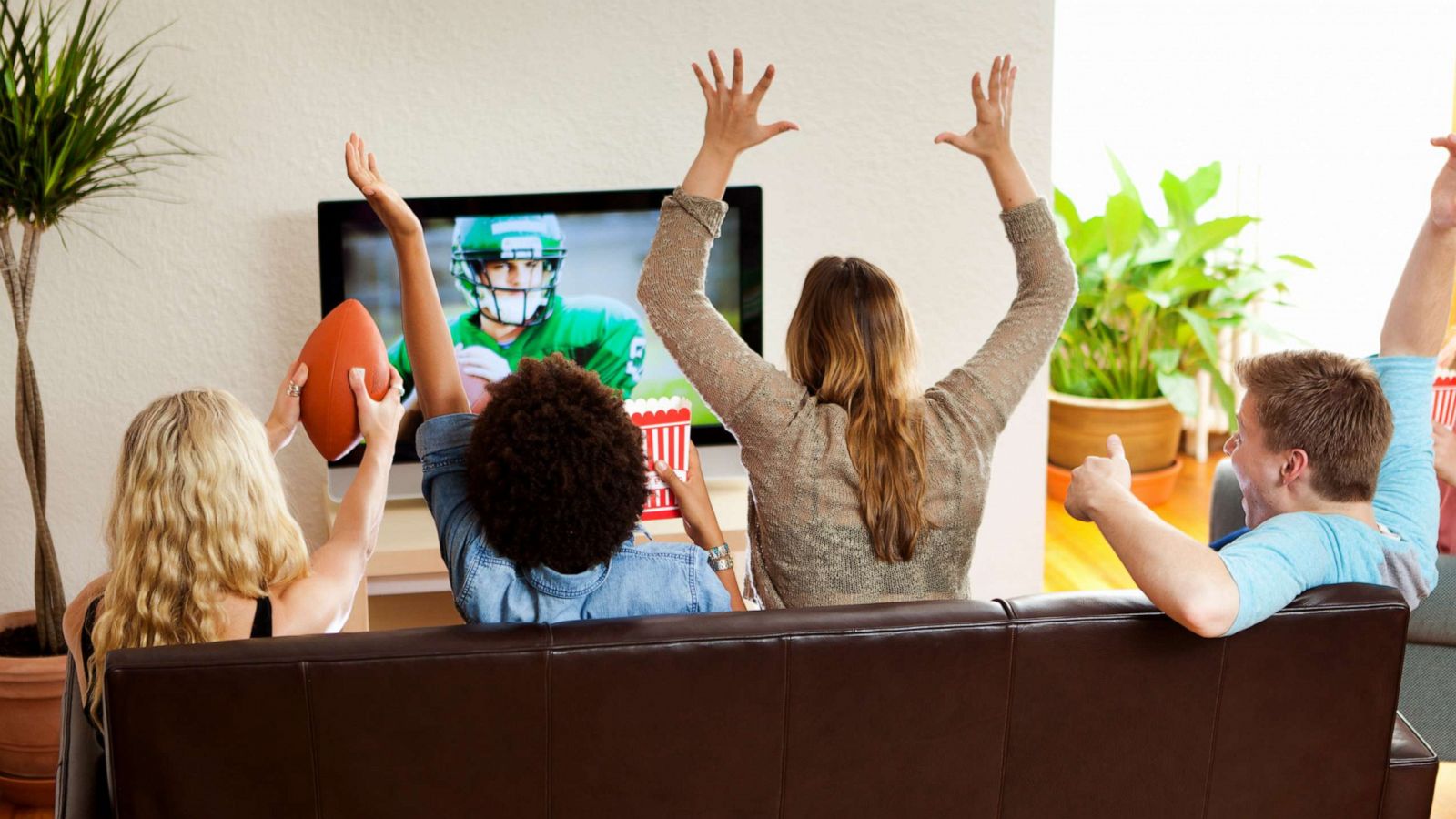 PHOTO: A group of cheering young people watch a football game on television in an undated stock image.