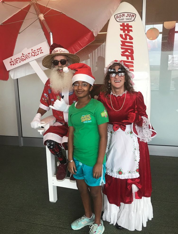 PHOTO: Charlotte Cornell, 14, poses for a photo with Mr. and Mrs. Claus from the Surfing Santa group from Florida's Space Coast during a visit to AdventHealth for Children's Hospital in Orlando, Fla.
