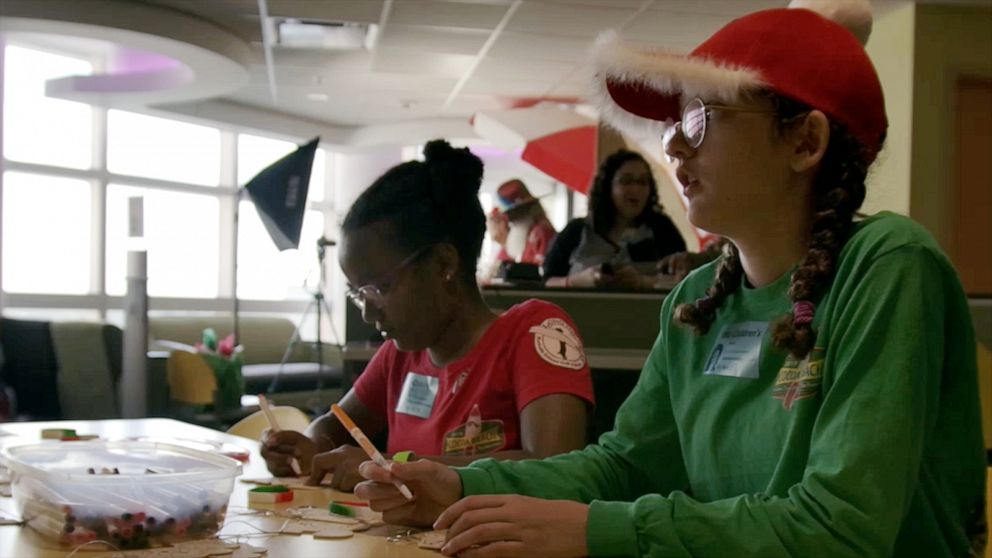 PHOTO: Anna Grace Cornell, 16, and Charlotte Cornell, 14, color pictures with patients at AdventHealth for Children Hospital in Orlando, Fla, during a holiday event with the Surfing Santas.