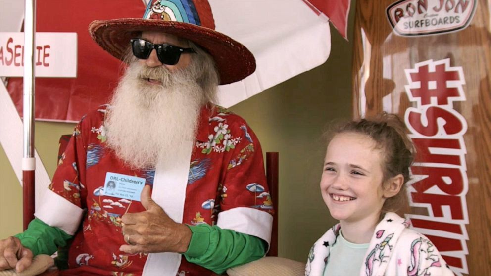 PHOTO: Santa Claus from Surfing Santas poses with Matalyn Dailey, a patient at AdventHealth for Children hospital in Orlando, Fla.