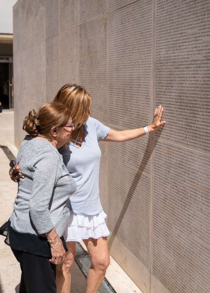 PHOTO: Charlotte and a family member search for Charlotte's parents on Paris's Wall of Names.