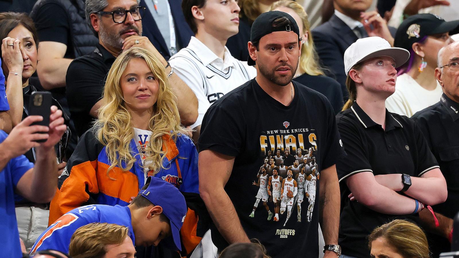 PHOTO: Sydney Sweeney and Scooter Braun look on during the fourth quarter in Game Five of the 2026 NBA Finals between the San Antonio Spurs and the New York Knicks at Frost Bank Center on June 13, 2026 in San Antonio, Texas.