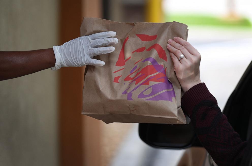 PHOTO: A Taco Bell employee delivers an order to a customer at the drive-up window of the restaurant on March 31, 2020 in Hollywood, Florida.