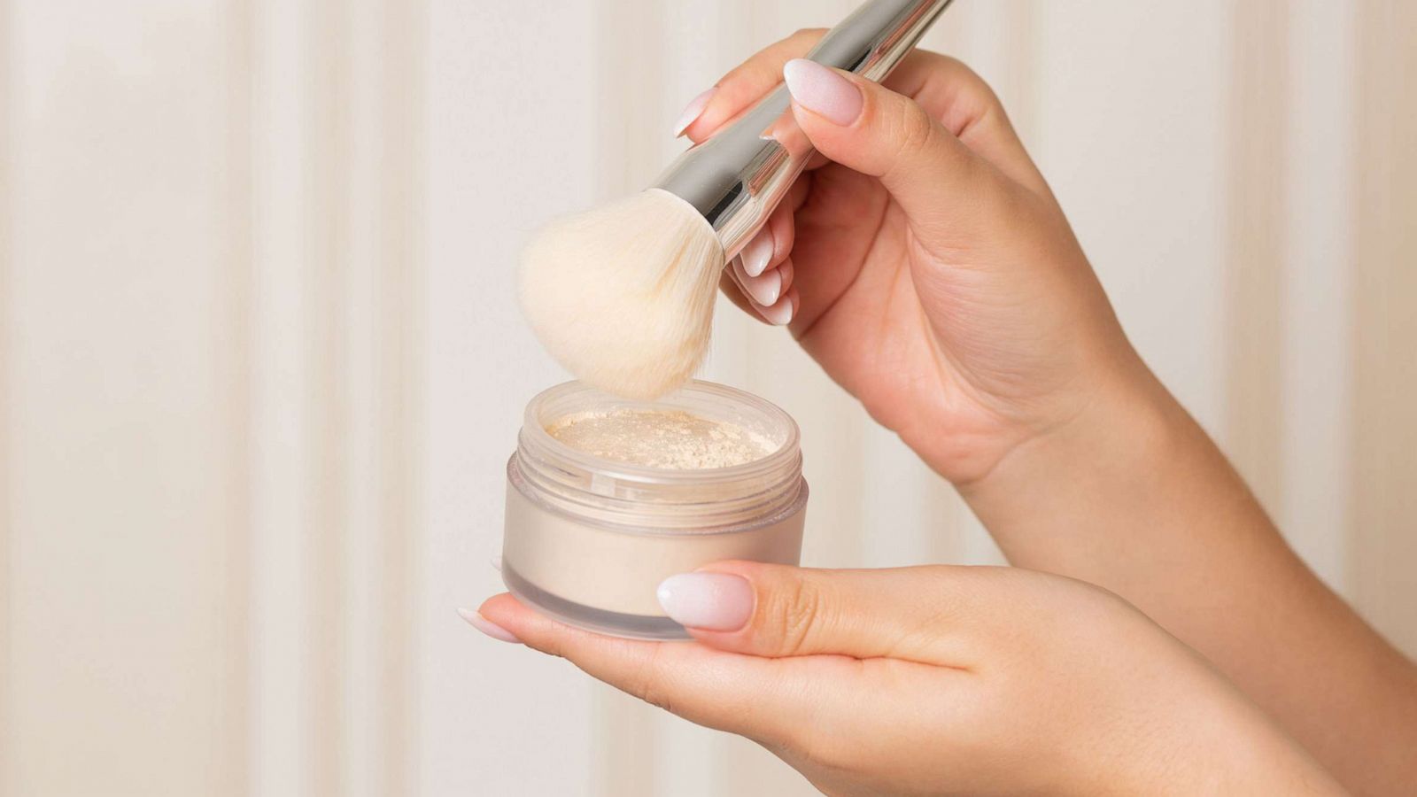 PHOTO: In an undated stock photo, a woman holds a brush and setting powder against a beige background.