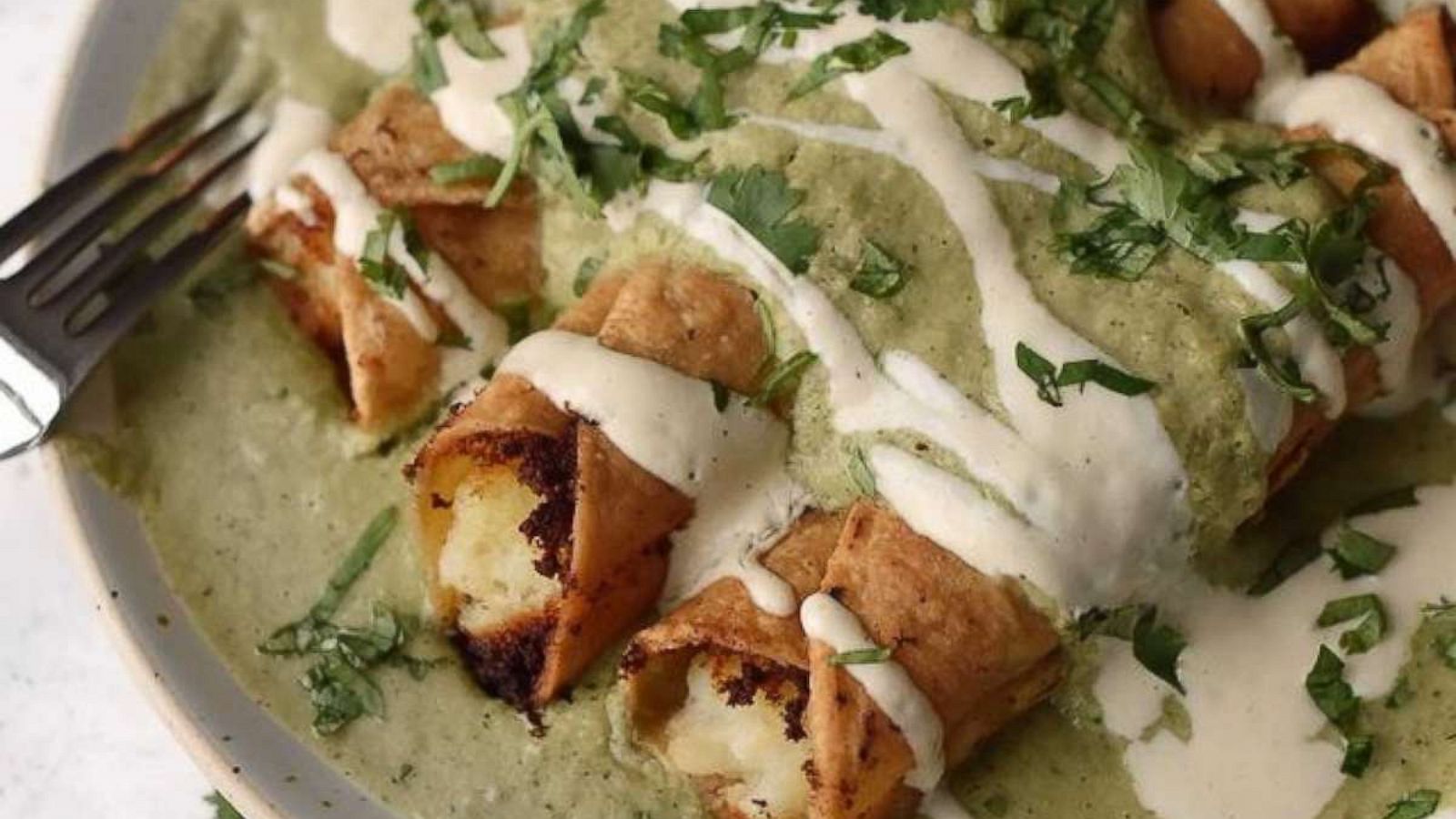 PHOTO: Crispy rolled tacos filled with potato and topped with creamy salsa verde.