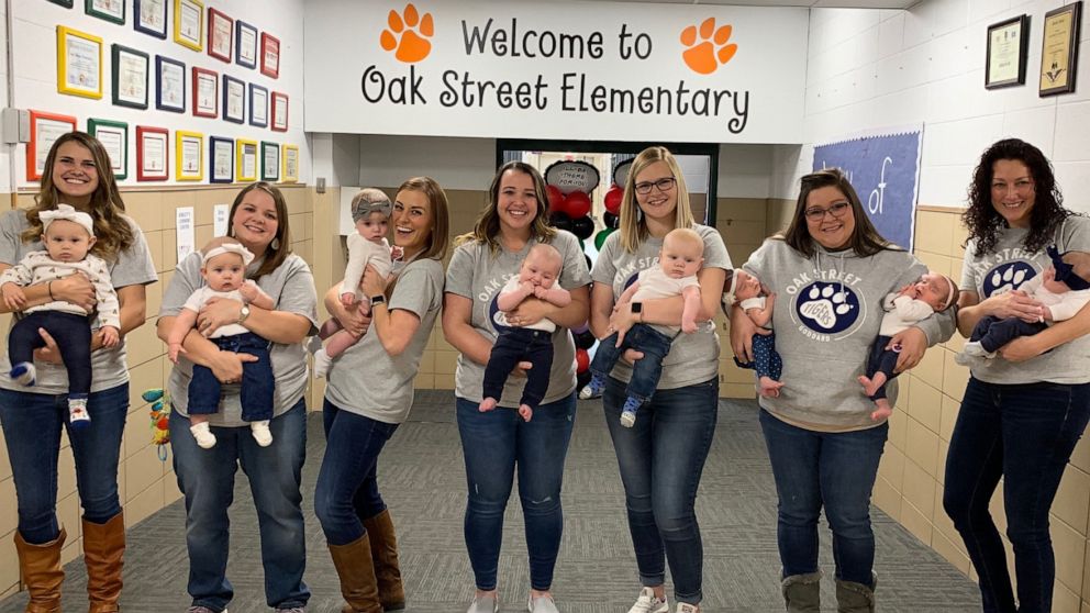 PHOTO: Seven teachers pose with their eight babies in the front hall at Oak Street Elementary in Goddard, Kan.
