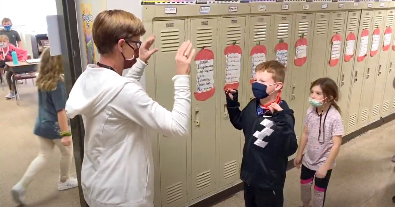 PHOTO: Mary Schulz, an elementary school teacher in Iowa, does a special distance greeting with each of her students.