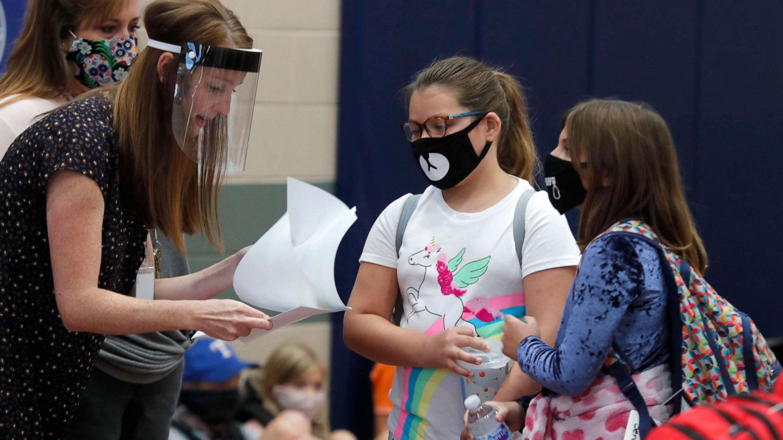 PHOTO: Wearing masks to prevent the spread of COVID-19, a teacher helps elementary school students before classes began for the day in Godley, Texas, Aug. 5, 2020.