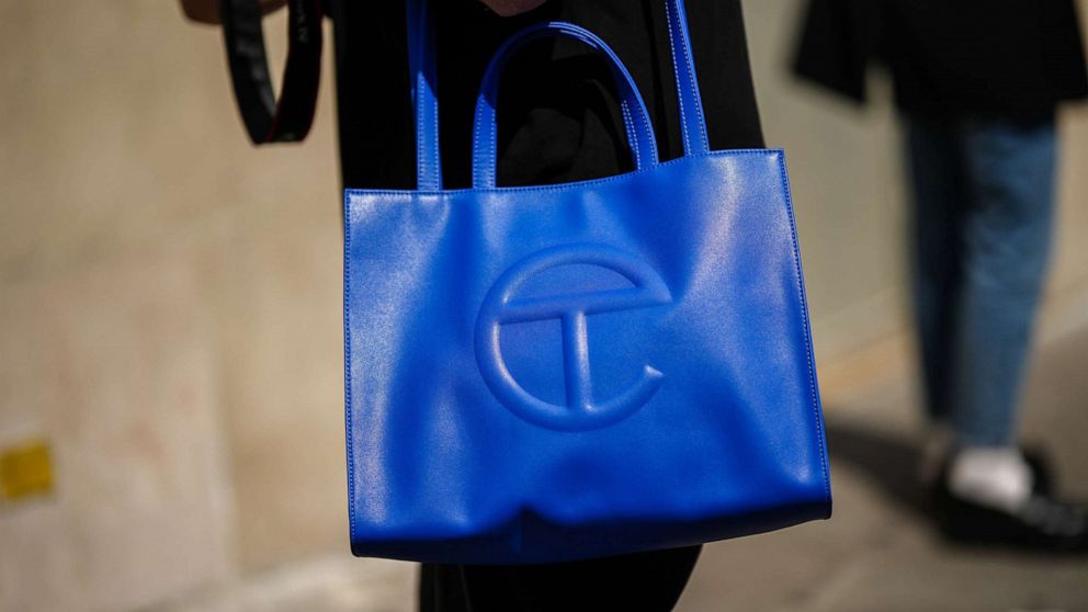 PHOTO: A guest wears a royal blue shiny leather Telfar large shoulder bag, during the Bluemarble show, during Paris Fashion Week Menswear Spring Summer 2023, June 21, 2022, in Paris.