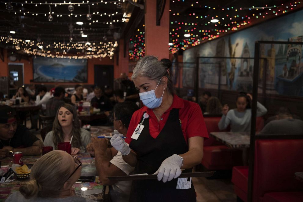 PHOTO: A waitress wearing a protective mask and gloves assists customers at Taqueria Del Sol restaurant in Houston, April 25, 2021.