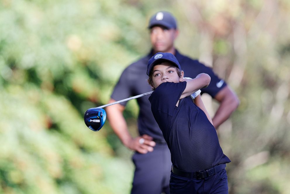 PHOTO: Charlie Woods plays a shot as Tiger Woods looks on during the Pro-Am ahead of the PNC golf Championship in Orlando, Fla., Dec. 17, 2021.
