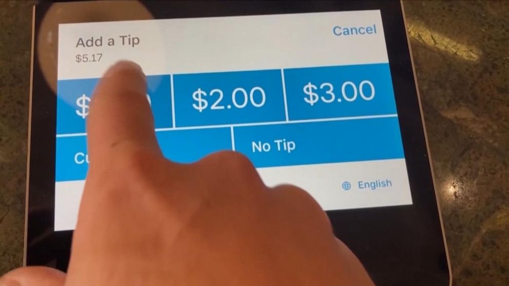 PHOTO: A person chooses a tip amount on a screen.