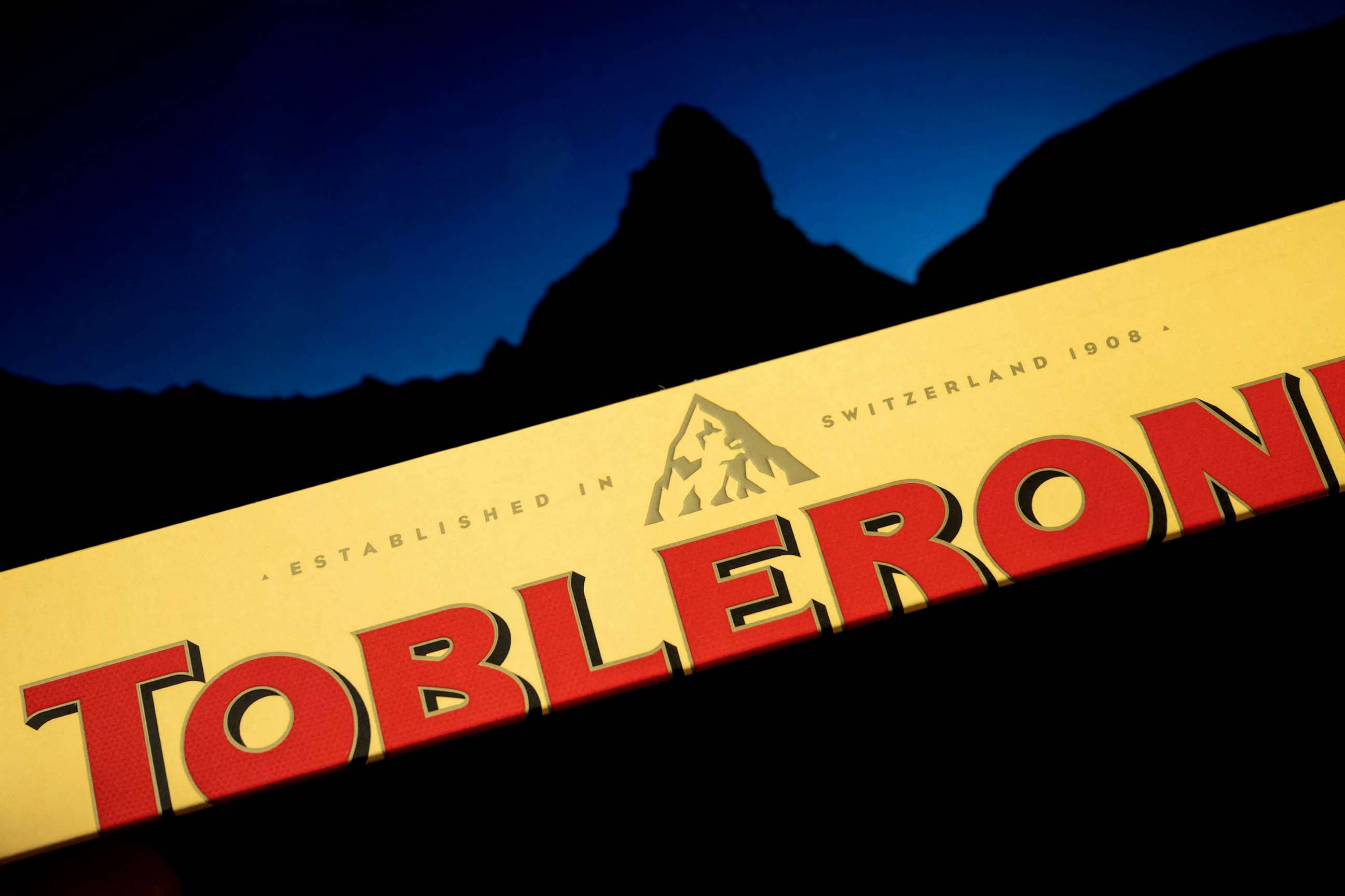 PHOTO: The packaging of a Toblerone chocolate bar owned by US firm Mondelez with a picture of the Matterhorn mountain seen in silhouette in the background, March 6, 2023, Geneva.