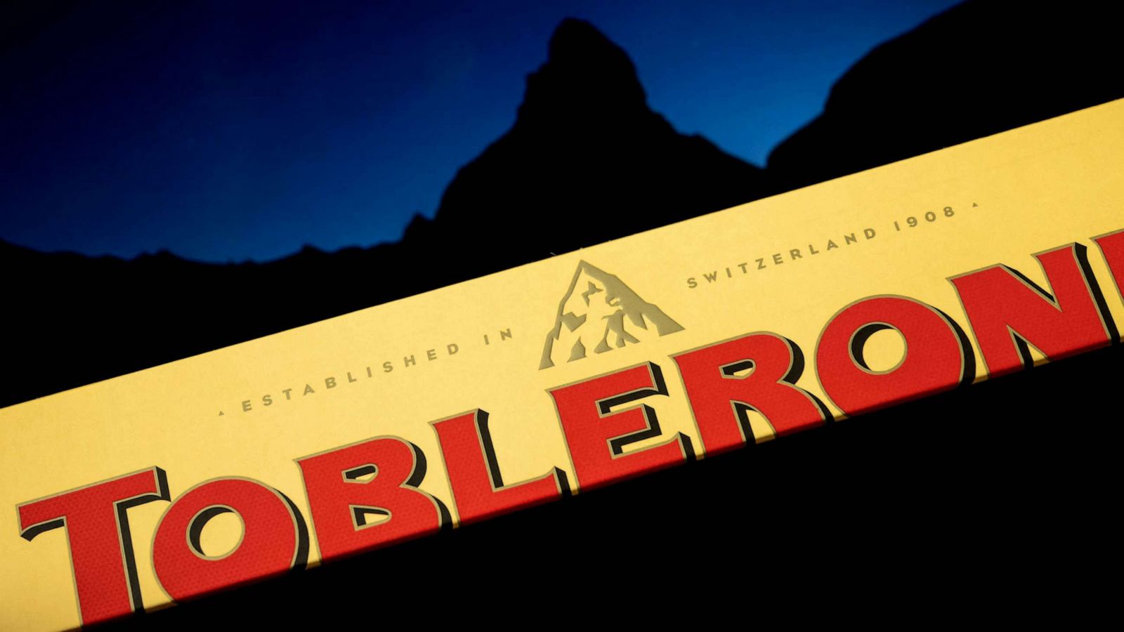 PHOTO: The packaging of a Toblerone chocolate bar owned by US firm Mondelez with a picture of the Matterhorn mountain seen in silhouette in the background, March 6, 2023, Geneva.