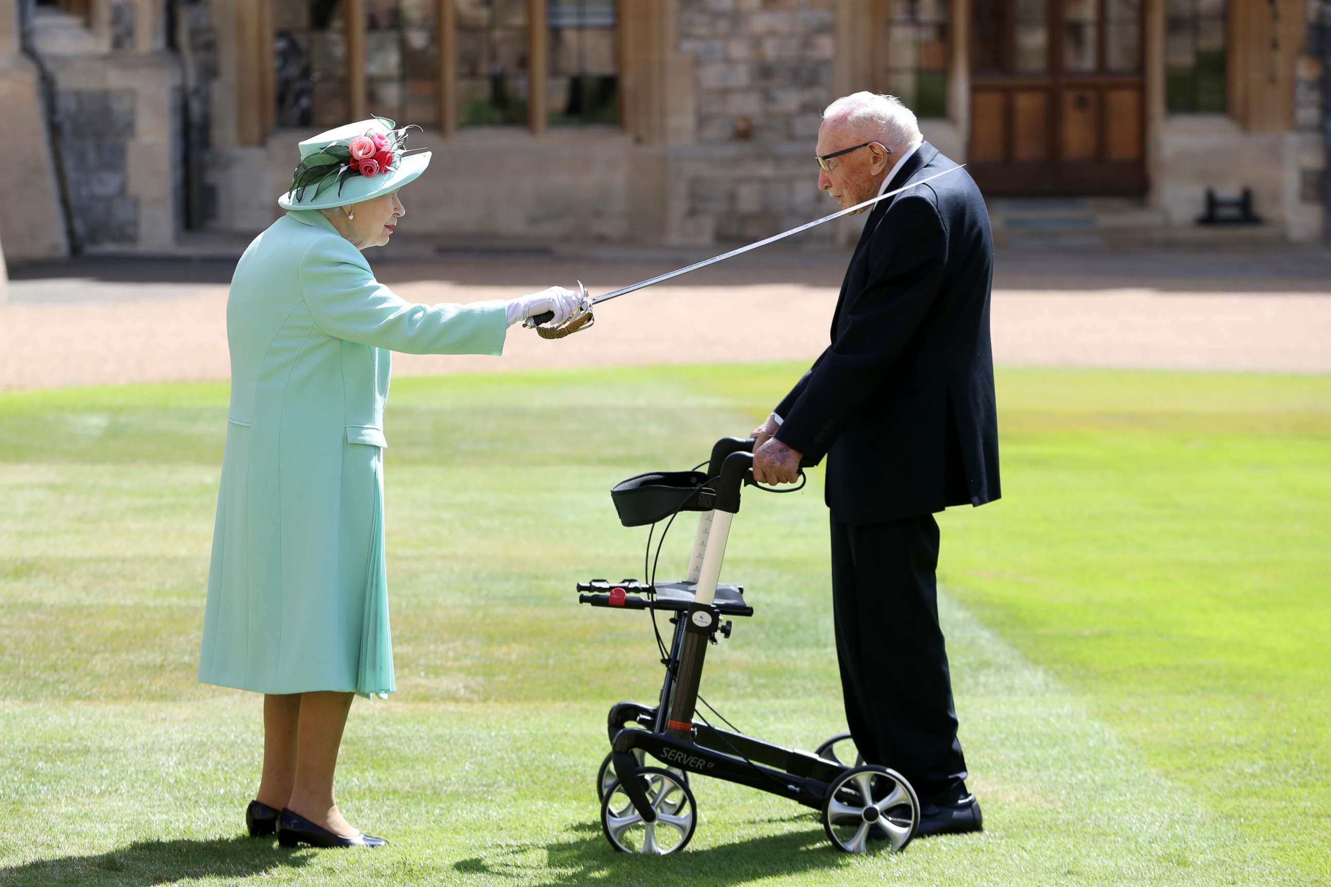 PHOTO: Queen Elizabeth II awards Captain Sir Thomas Moore with the insignia of Knight Bachelor at Windsor Castle, July 17, 2020, in Windsor, England.