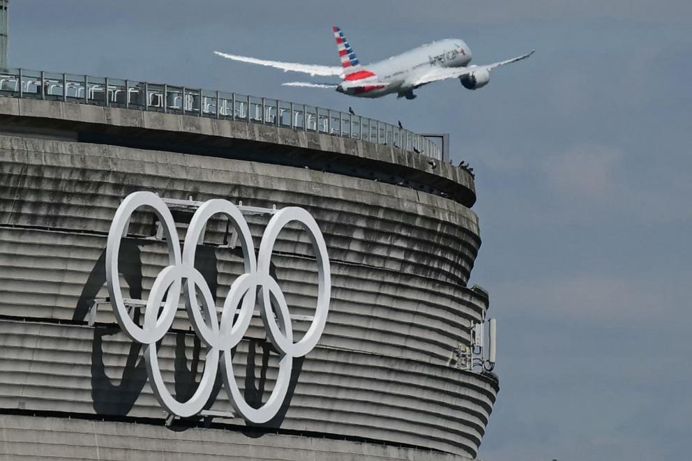 PHOTO: This photograph taken in Roissy-en-France on April 23, 2024, shows an aircraft taking off past the Olympic rings displayed on the Roissy - Charles de Gaulle Airport Terminal 1, north of Paris, ahead of The Paris 2024 Olympics.