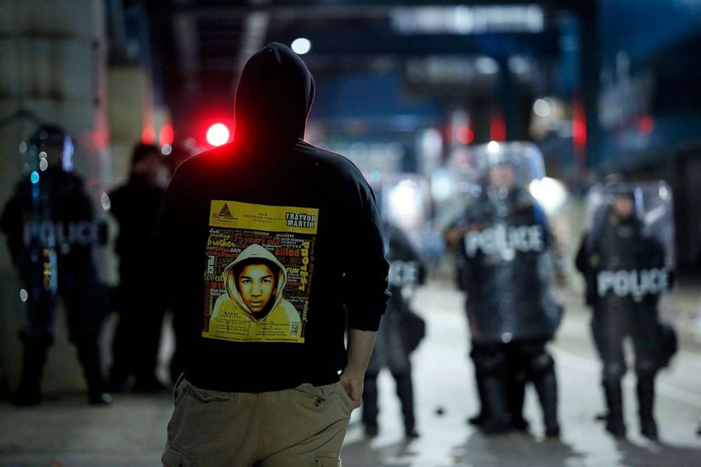 PHOTO: In this Oct. 27, 2020, file photo, a demonstrator protesting the fatal police shooting of Walter Wallace Jr. wears a hoodie with a photo of Trayvon Martin on it as police officers in riot gear stand side by side in Philadelphia.