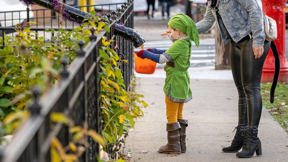 PHOTO: Children receive treats by candy chutes while trick-or-treating for Halloween in Woodlawn Heights on Oct. 31, 2020 in New York City.