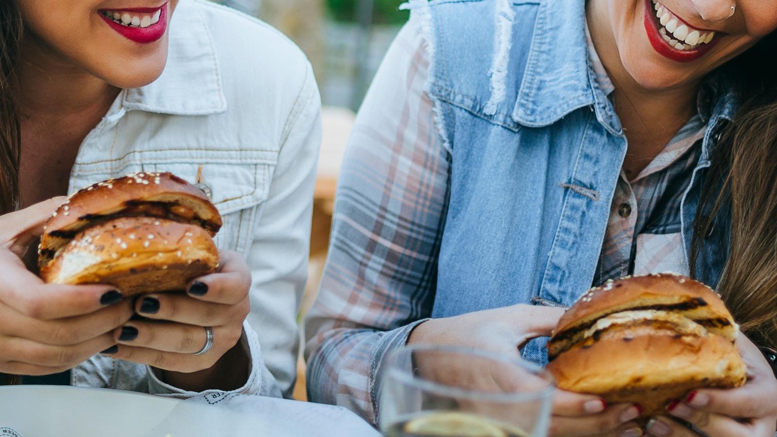 PHOTO: Two women eat hamburgers, french fries and salad during lunch.